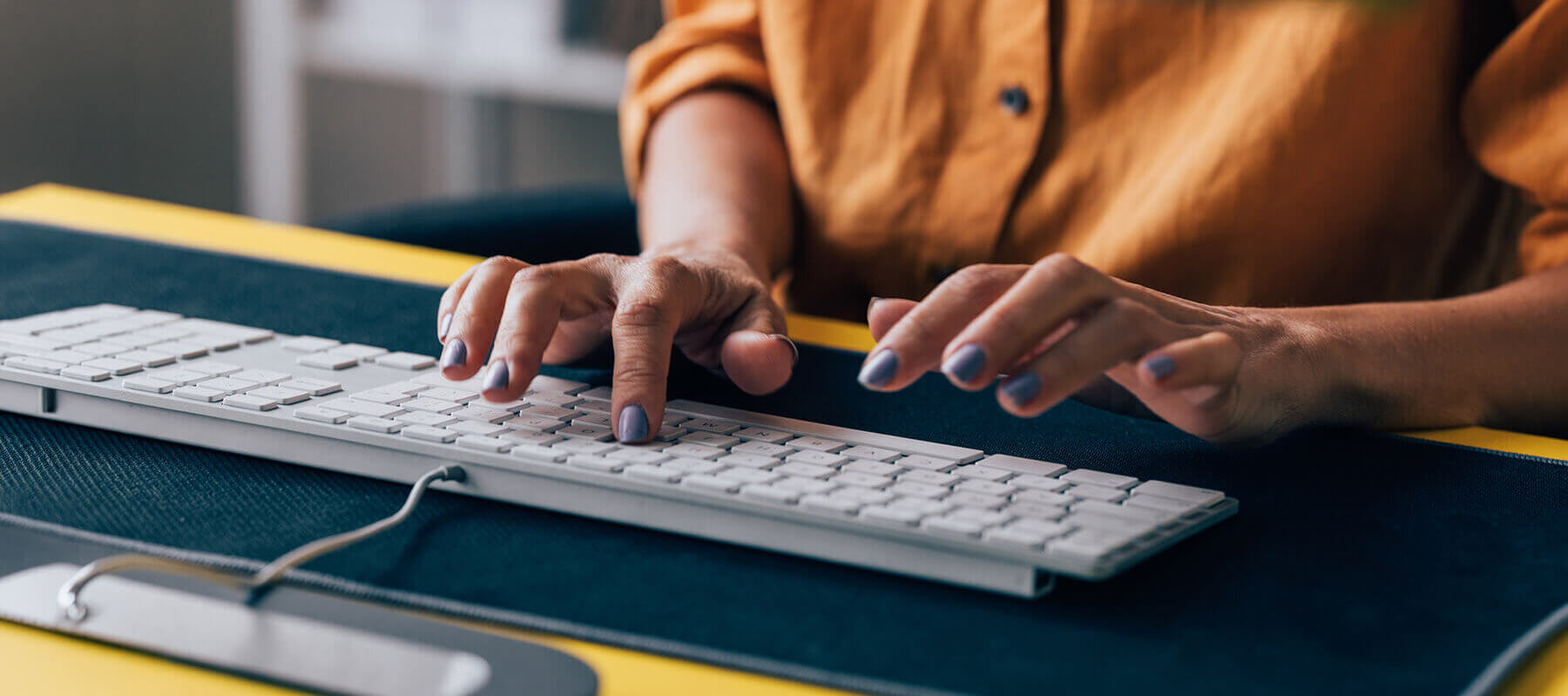 Close-up of a woman's hands typing on a white computer keyboard